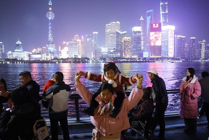 2024年2月9日，上海，游客带着孩子在外滩滨江步道上欣赏黄浦江两岸美景。中新社记者 殷立勤 图